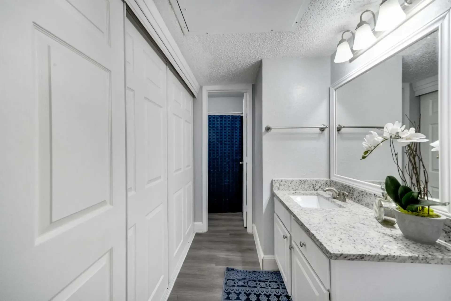 A bathroom with a sink , mirror and sliding doors.
