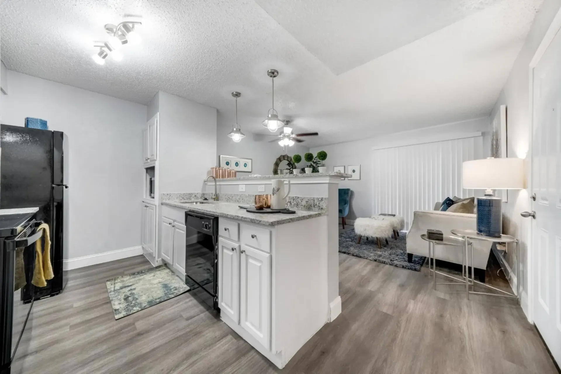 A kitchen with white cabinets , black appliances , a black refrigerator and a ceiling fan.