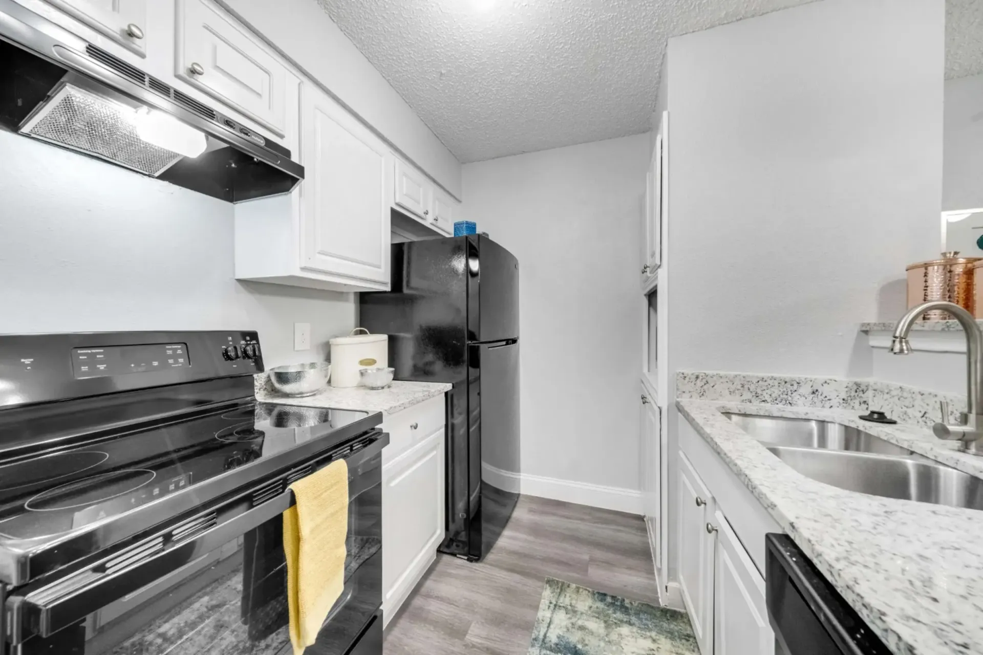 A kitchen with a stove , refrigerator , sink , and cabinets.