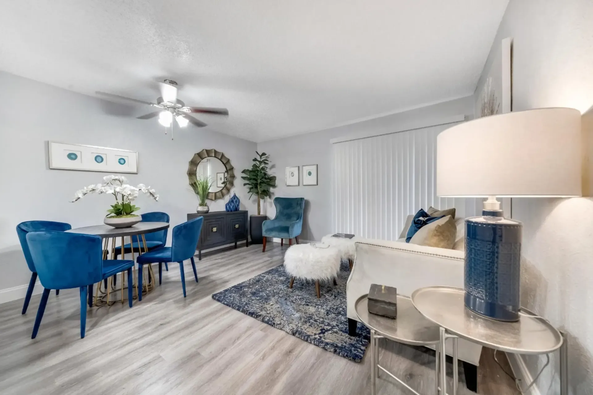 A living room with a couch , chairs , a table and a ceiling fan.