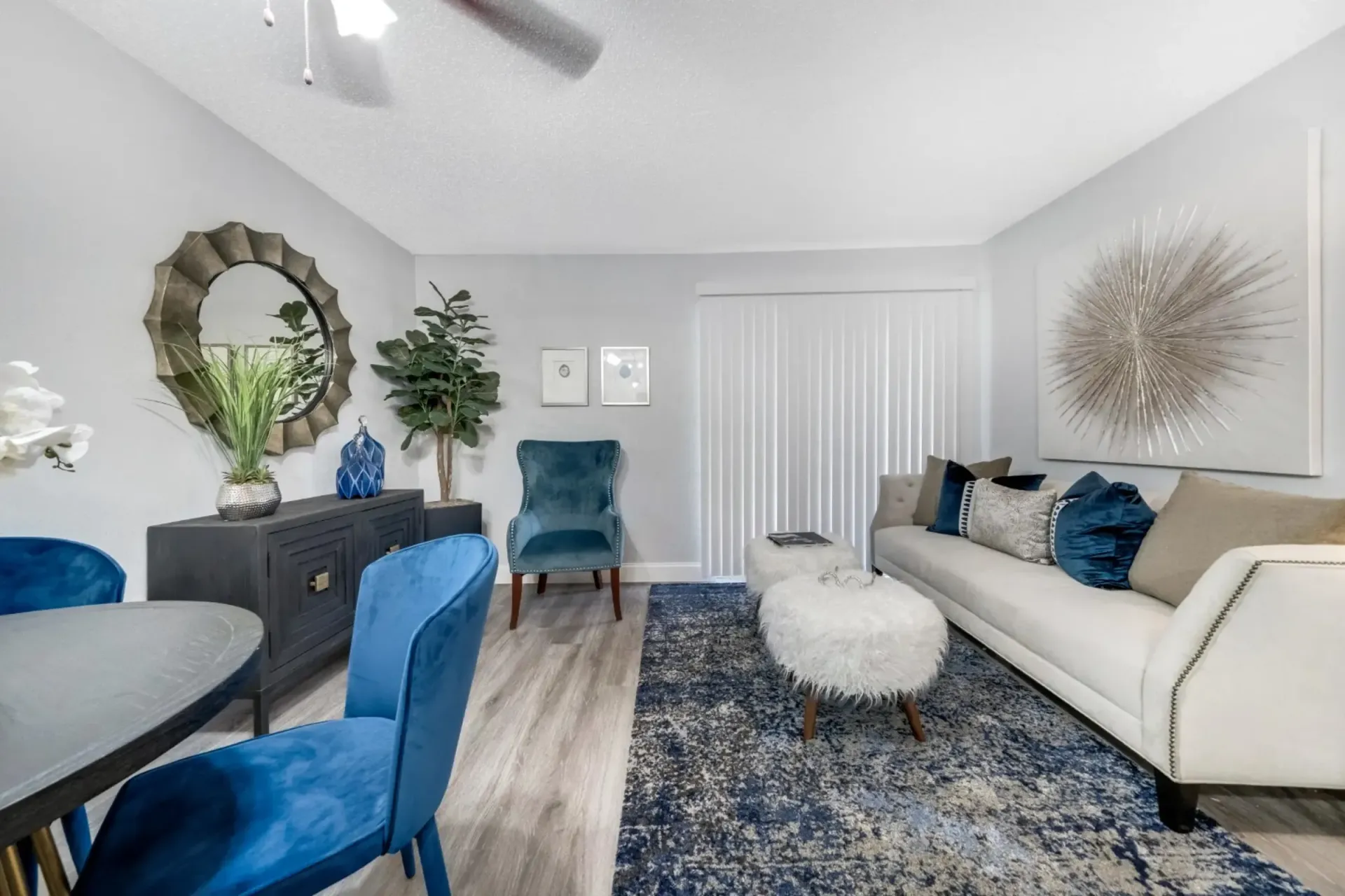 A living room with a couch , chairs , a table and a ceiling fan.
