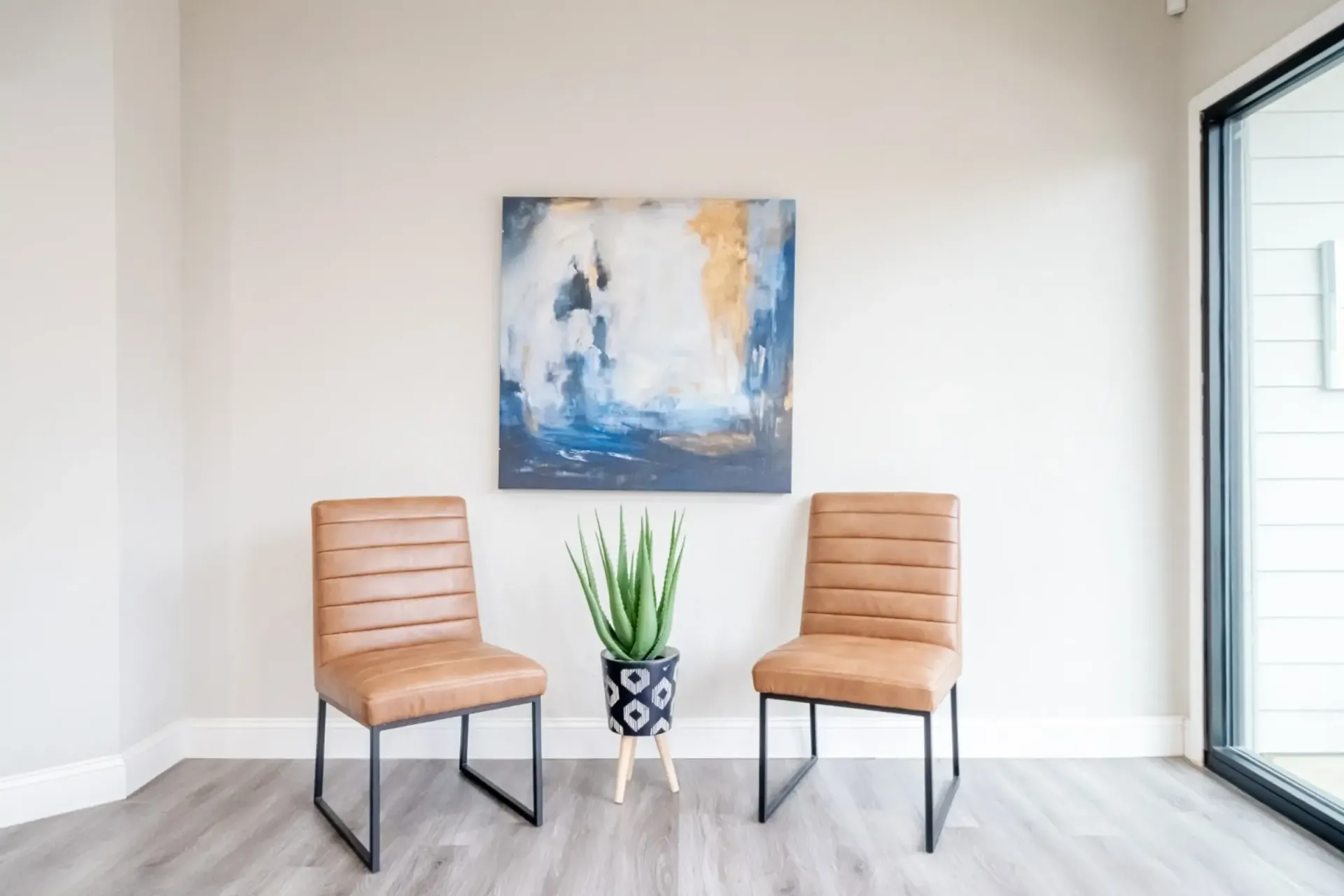A waiting room with two chairs and a painting on the wall.