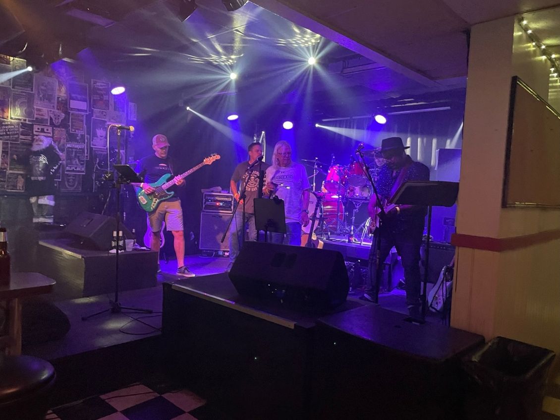 Band performing on stage under blue lights in a bar.