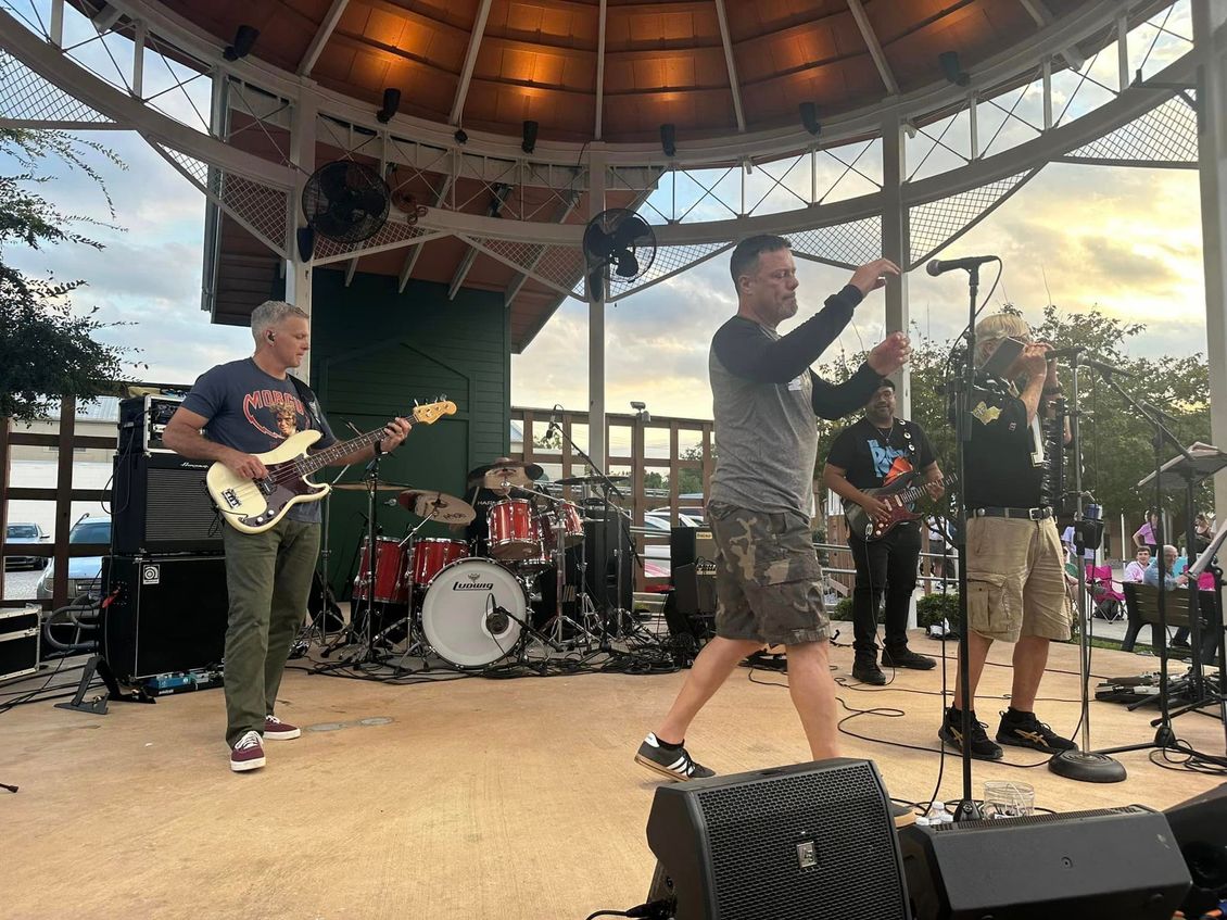 Band playing live music on outdoor stage with gazebo.