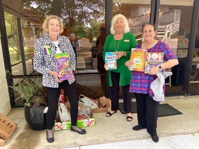 Three women are standing in front of a building holding cereal