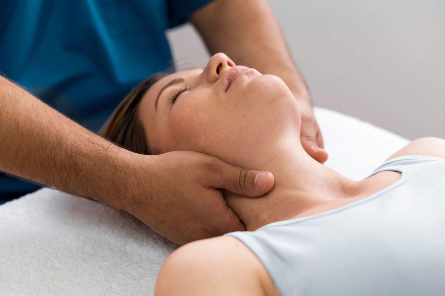 Una mujer está recibiendo un masaje de cuello por parte de un médico.