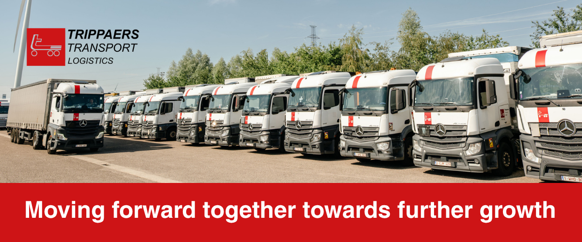 Row of white delivery trucks in a yard with red banner reading “Moving forward together towards further growth”