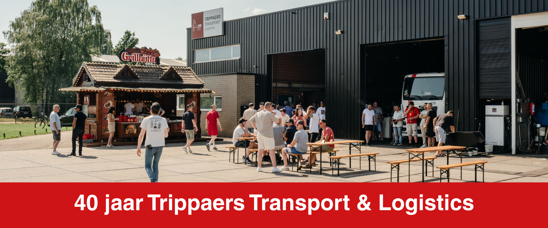 Crowd outside Trippaers Transport & Logistics building with red banner reading “40 jaar Trippaers Transport & Logistics”