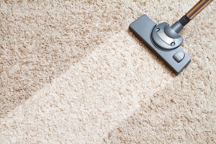 Vacuum cleaner head on beige carpet, cleaning a visible dirty patch