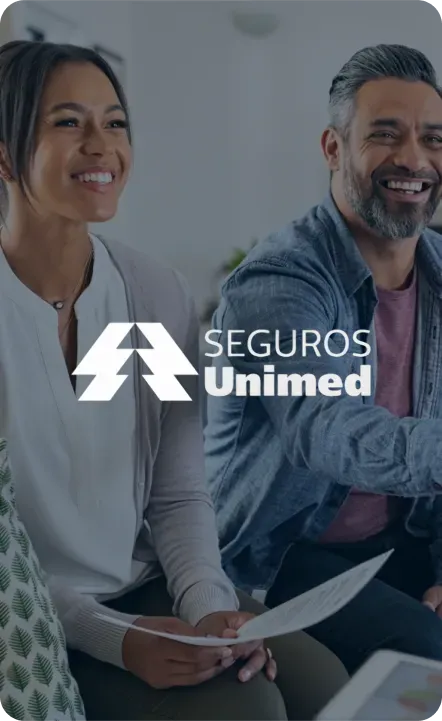 Two people smiling while holding papers. Unimed Seguros logo in the center left.