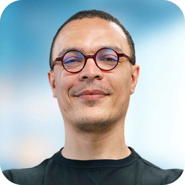 Headshot of a smiling person wearing round glasses against a blue sky background