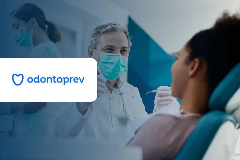 Dentist examining a patient's teeth. The dentist wears a mask and gloves, office setting, Odontoprev logo visible.