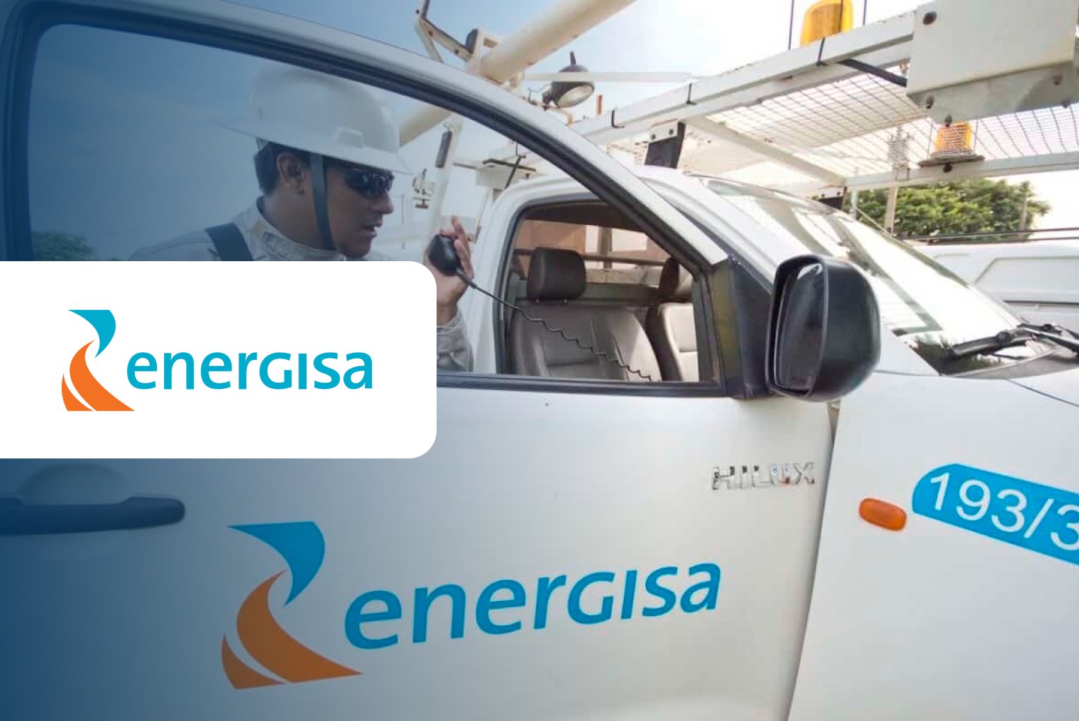 Energisa worker in truck, using radio, with logo visible. White truck, blue and orange logo.