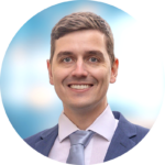 Man in suit smiling against a blue blurred background.