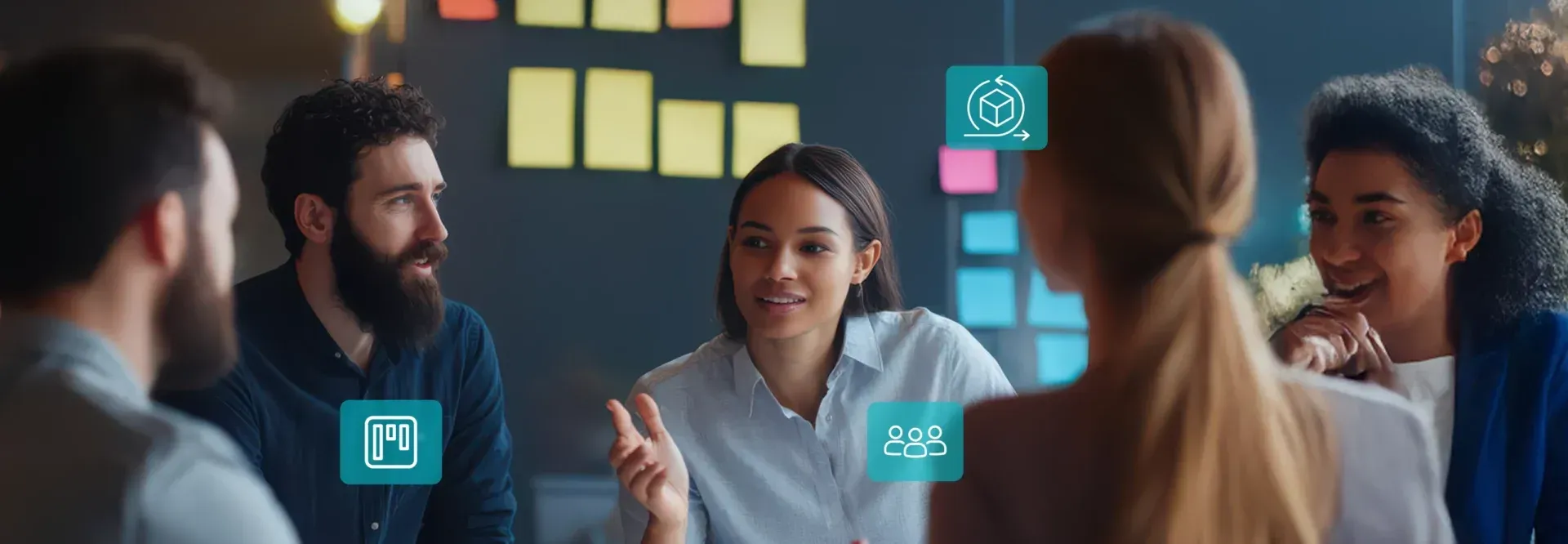 People in a meeting, with sticky notes on a wall. Woman speaking, others listening.