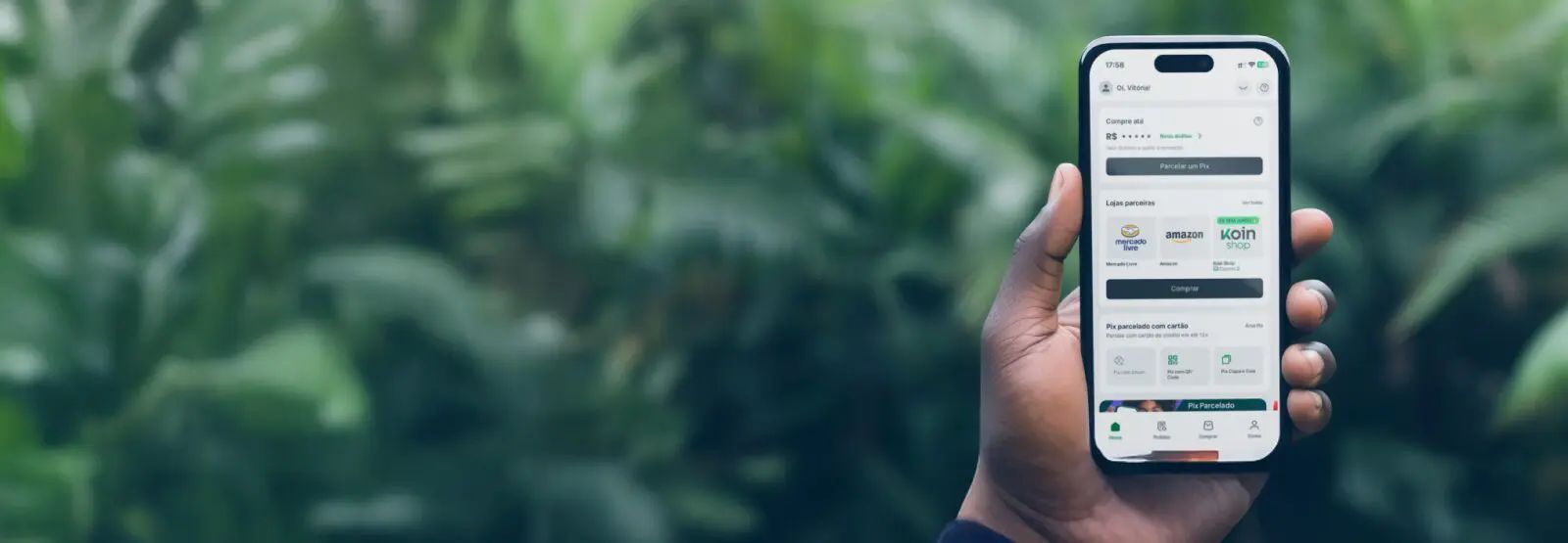 Hand holding a phone displaying an app interface. The background is a blurred green foliage.