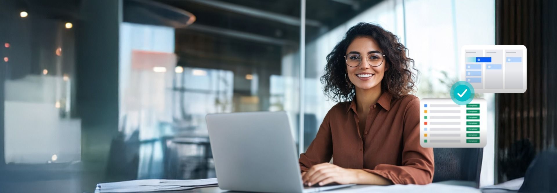Woman smiling at laptop in modern office, with digital documents displayed.
