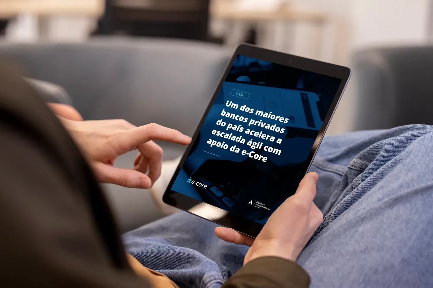 Person holding a tablet, reading text on screen, sitting on a couch. Dark blue screen with white text.