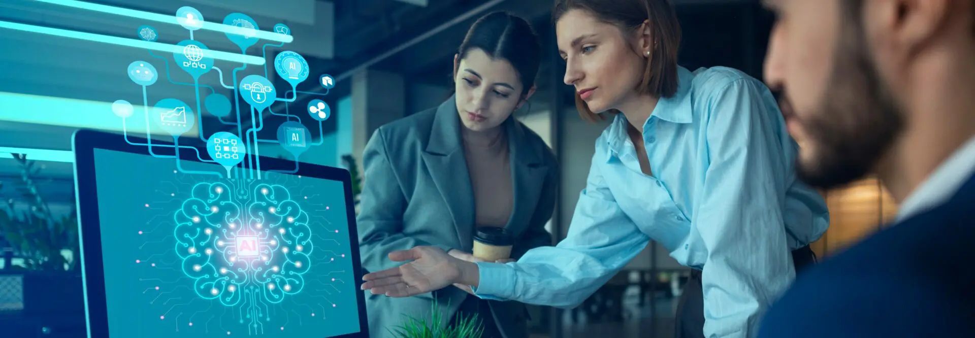 Three business people reviewing data on a computer screen, one pointing at it.
