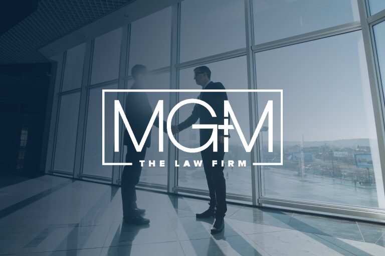 Two people shaking hands, standing in front of large windows. Law firm logo: