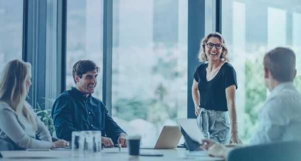 A group of people are sitting around a table in a conference room having a meeting.