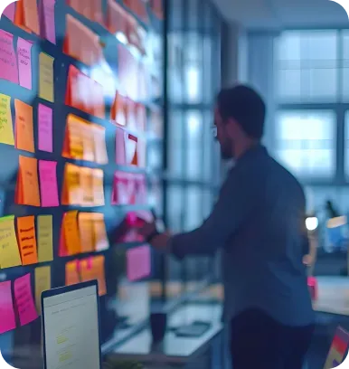 Man working with sticky notes on a glass wall in an office.