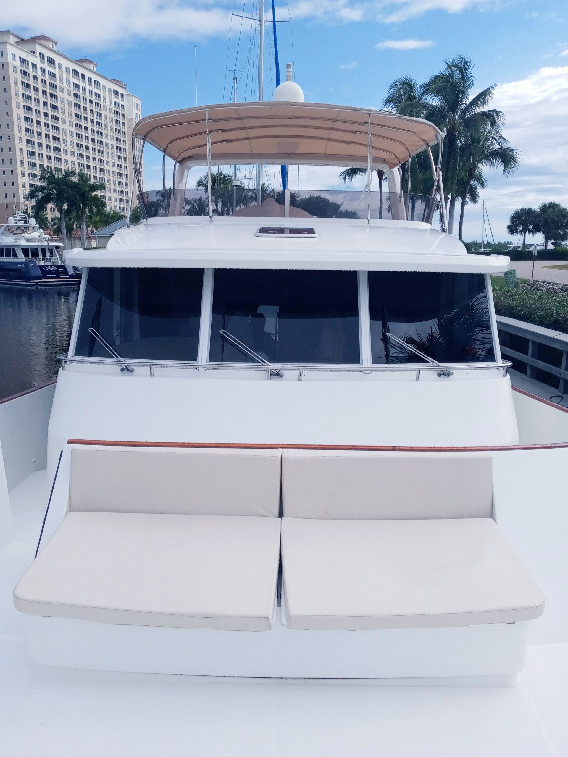 The front of a white yacht is docked in a marina.