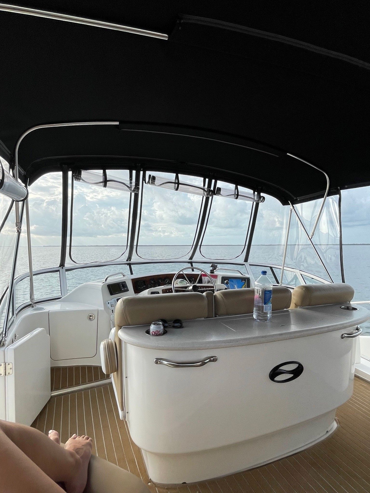 A person is sitting on the deck of a boat with a black canopy.