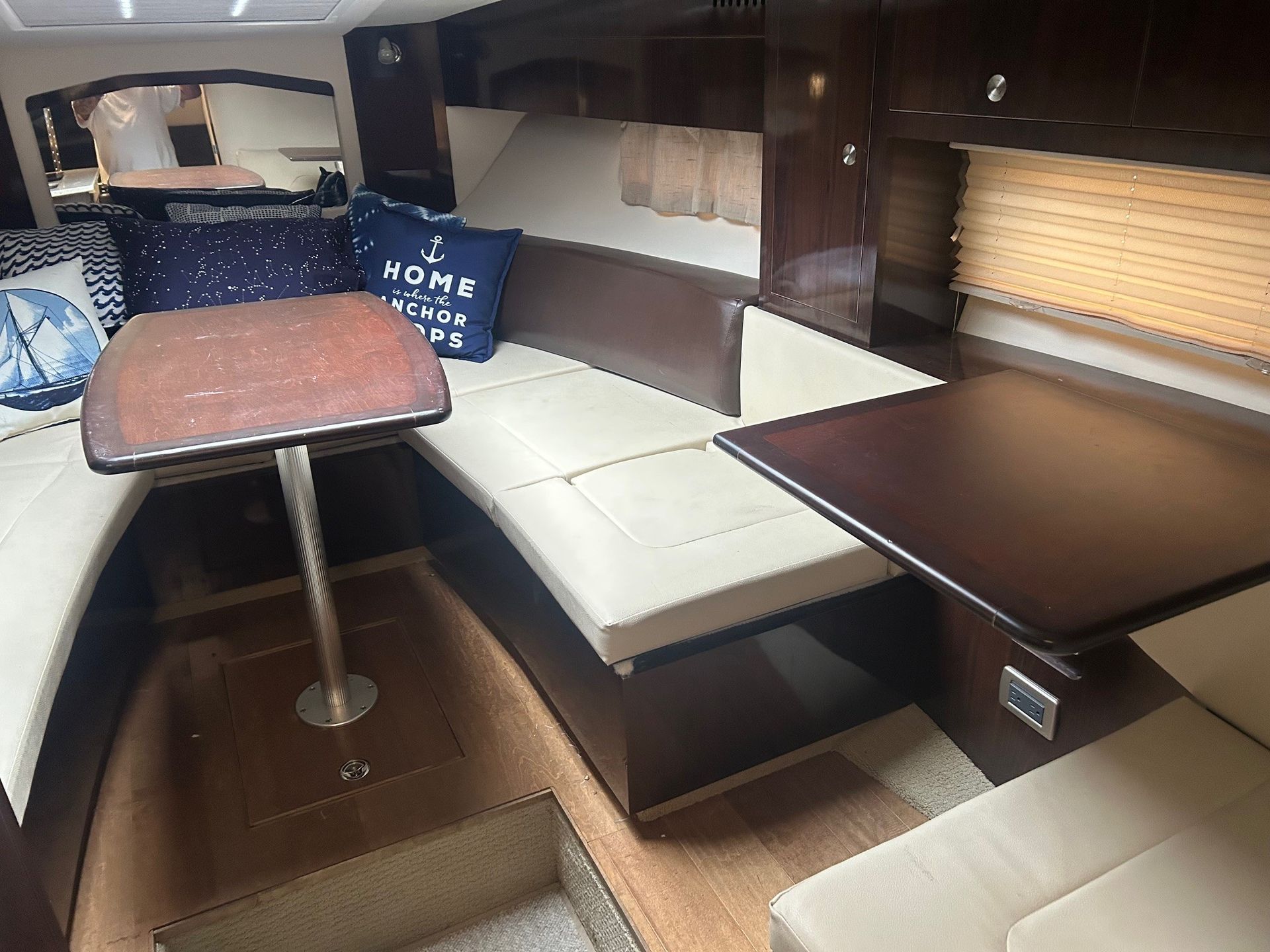 Boat cabin interior with seating, tables, and pillows.