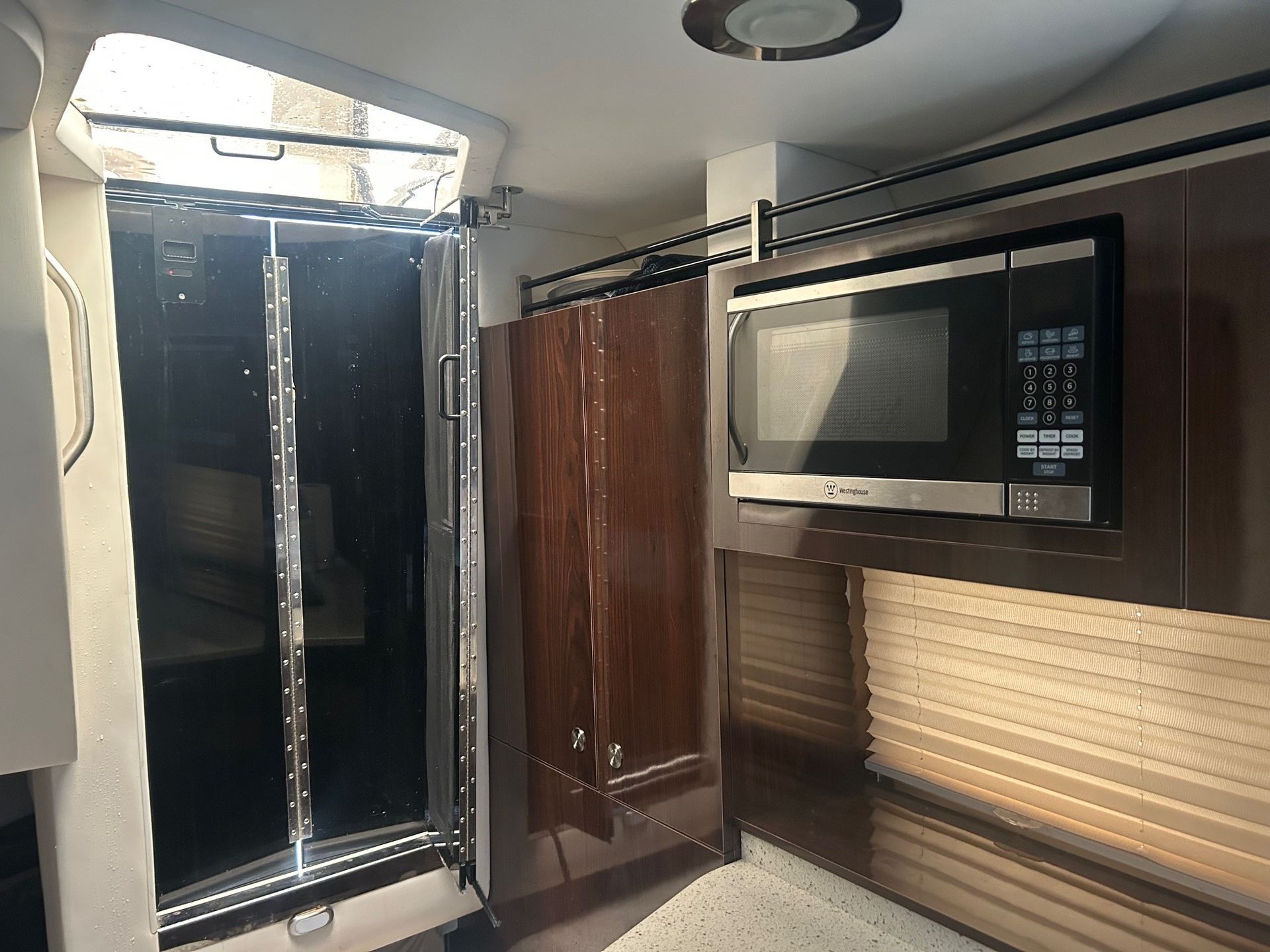 Boat interior with microwave, cabinets, and open door.