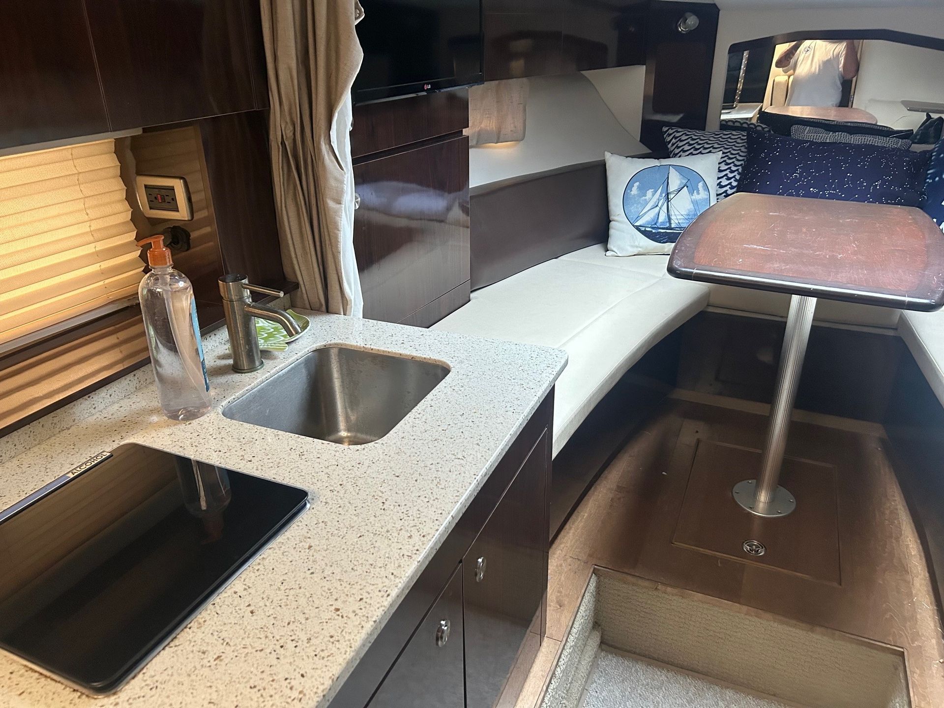 Interior of a boat cabin with a kitchenette, seating, and a bed.