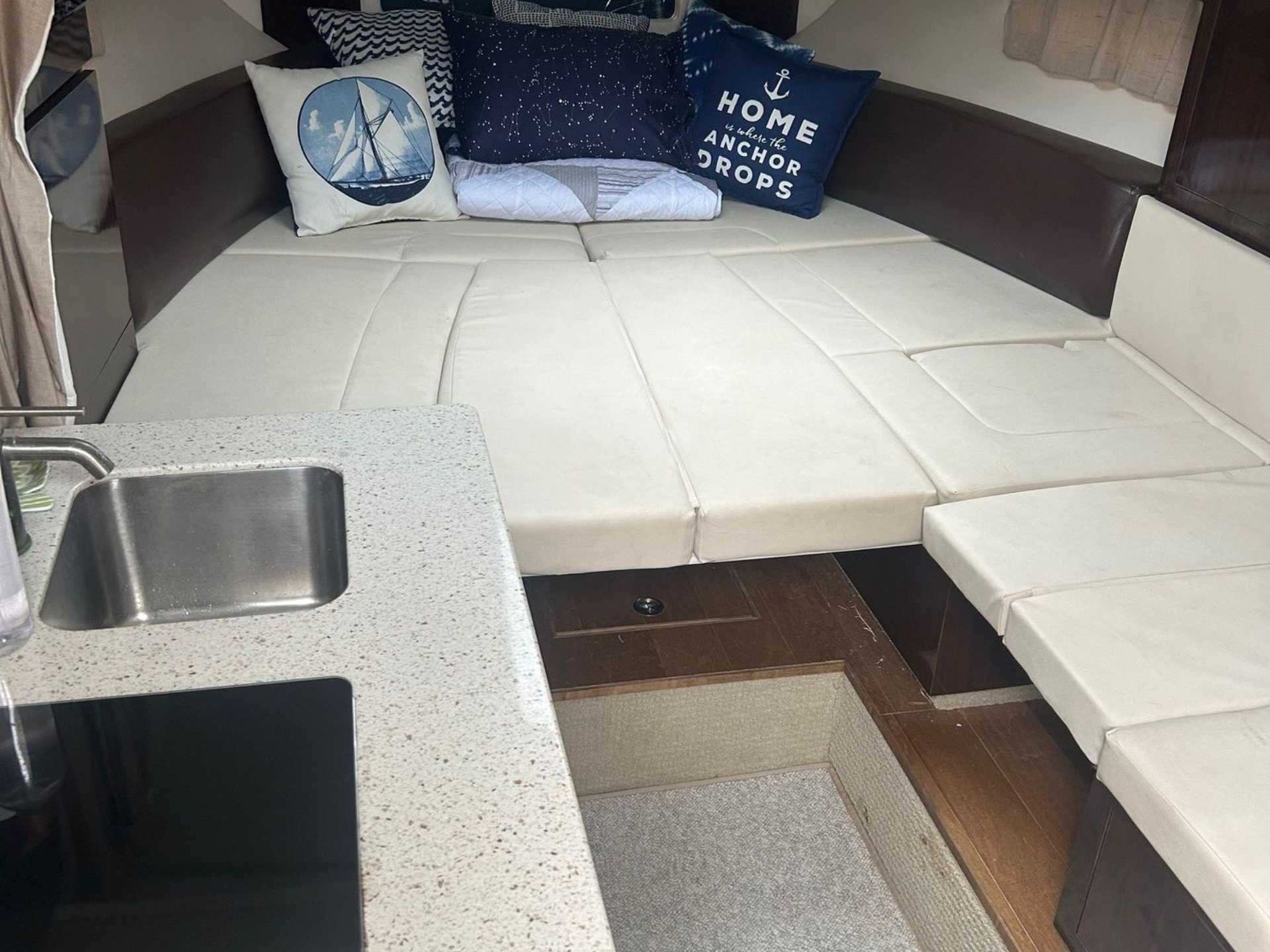 Small boat interior with white countertop, cushions, and window.