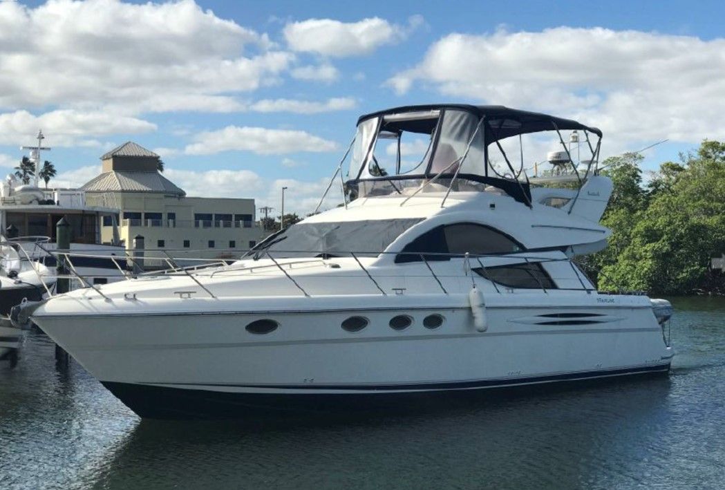 A white yacht is docked in a marina next to a body of water.