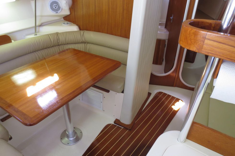 A small wooden table is sitting in the middle of a room on a boat.