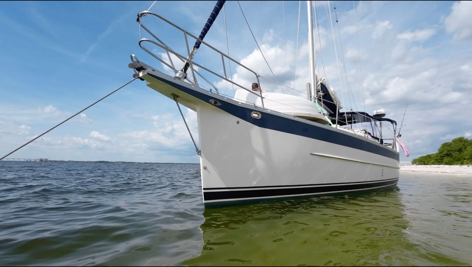 A sailboat is docked in the water near a beach.