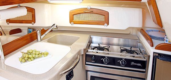 A kitchen on a boat with a stove , sink , and microwave.