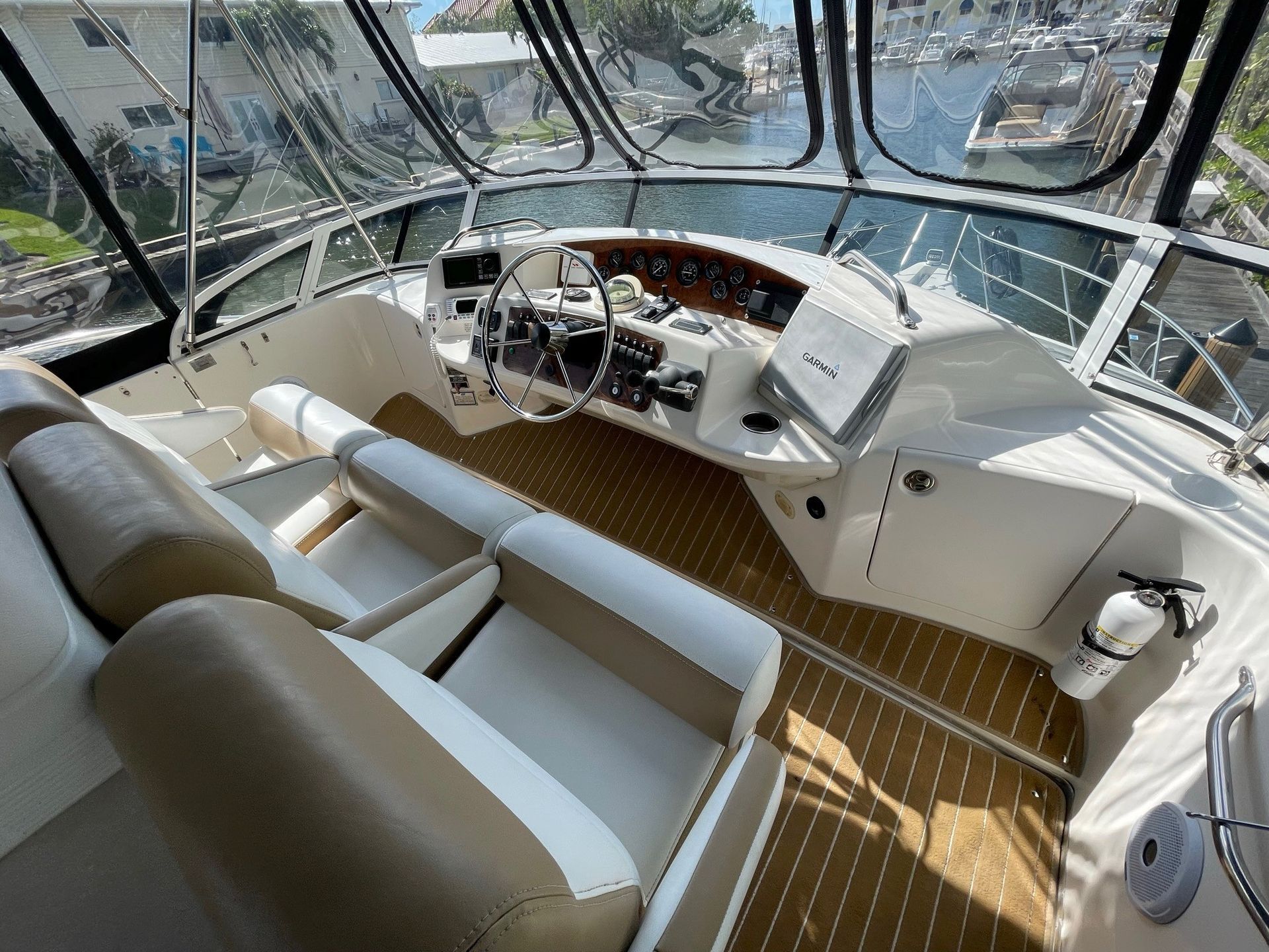 The cockpit of a boat with a wooden floor and a steering wheel.