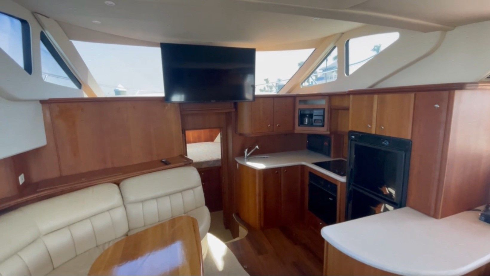 The inside of a boat with a couch , table , television and kitchen.