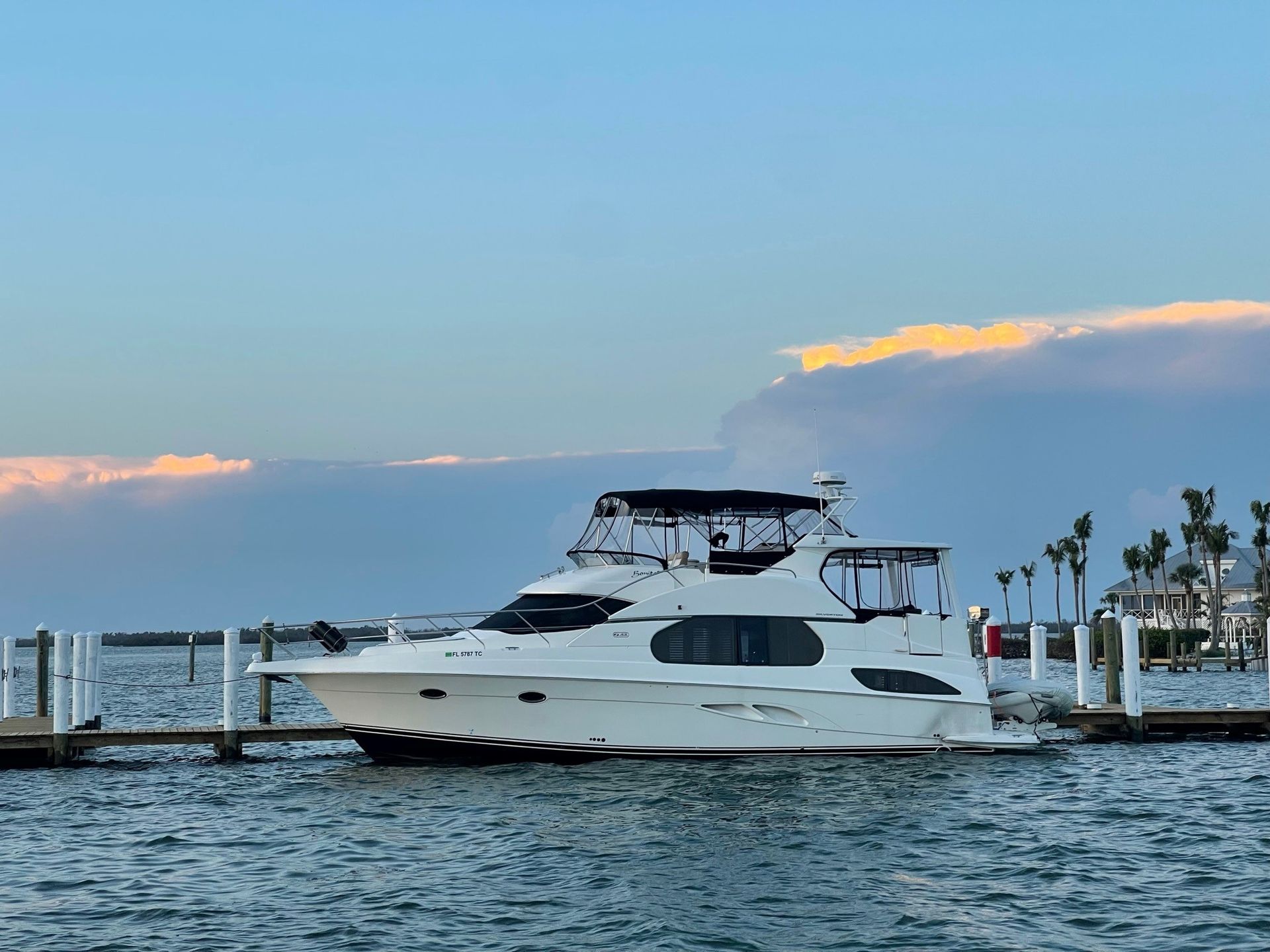 A white yacht is docked at a dock in the water.