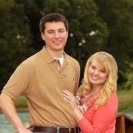 Couple smiling outdoors, with the woman in a coral top and the man in a tan shirt.