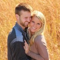 Smiling couple embracing in a sunlit field with tall golden grass