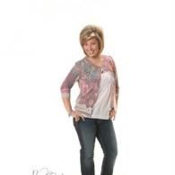 Woman posing in a pink cardigan and jeans against a white background