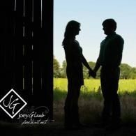 Silhouetted couple holding hands in a doorway, facing each other with bright green field in background
