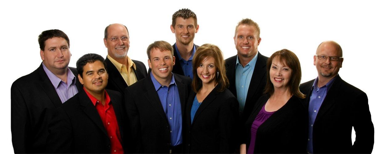 Nine business professionals standing together in suits on a white background.