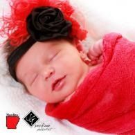 Sleeping baby wrapped in a pink blanket with a black flower headband