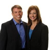 Two people in business attire smiling against a white background
