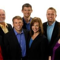 Group of five smiling people in business attire against a white background