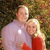 Smiling couple hugging outdoors in front of red and green foliage