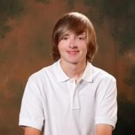 Smiling person in a white polo shirt against a dark studio backdrop