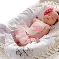 Sleeping little baby in a pink outfit and headband, resting in a white woven basket